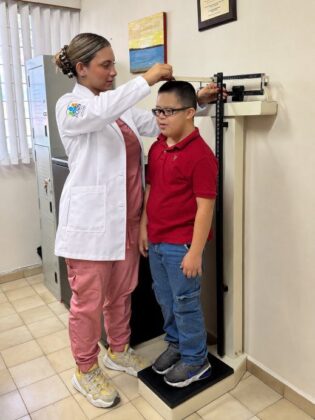 Doctora midiendo la estatura de un alumno