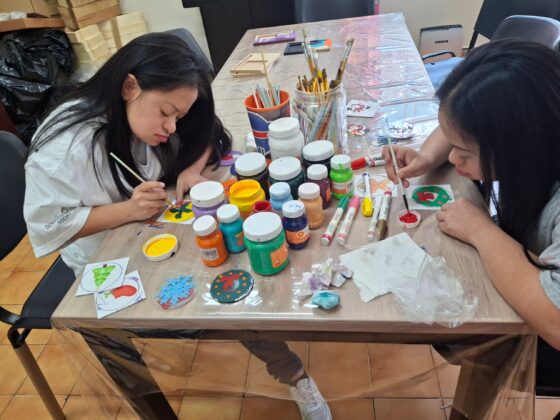 Dos alumnas pintando adornos navideños en el taller de pintura
